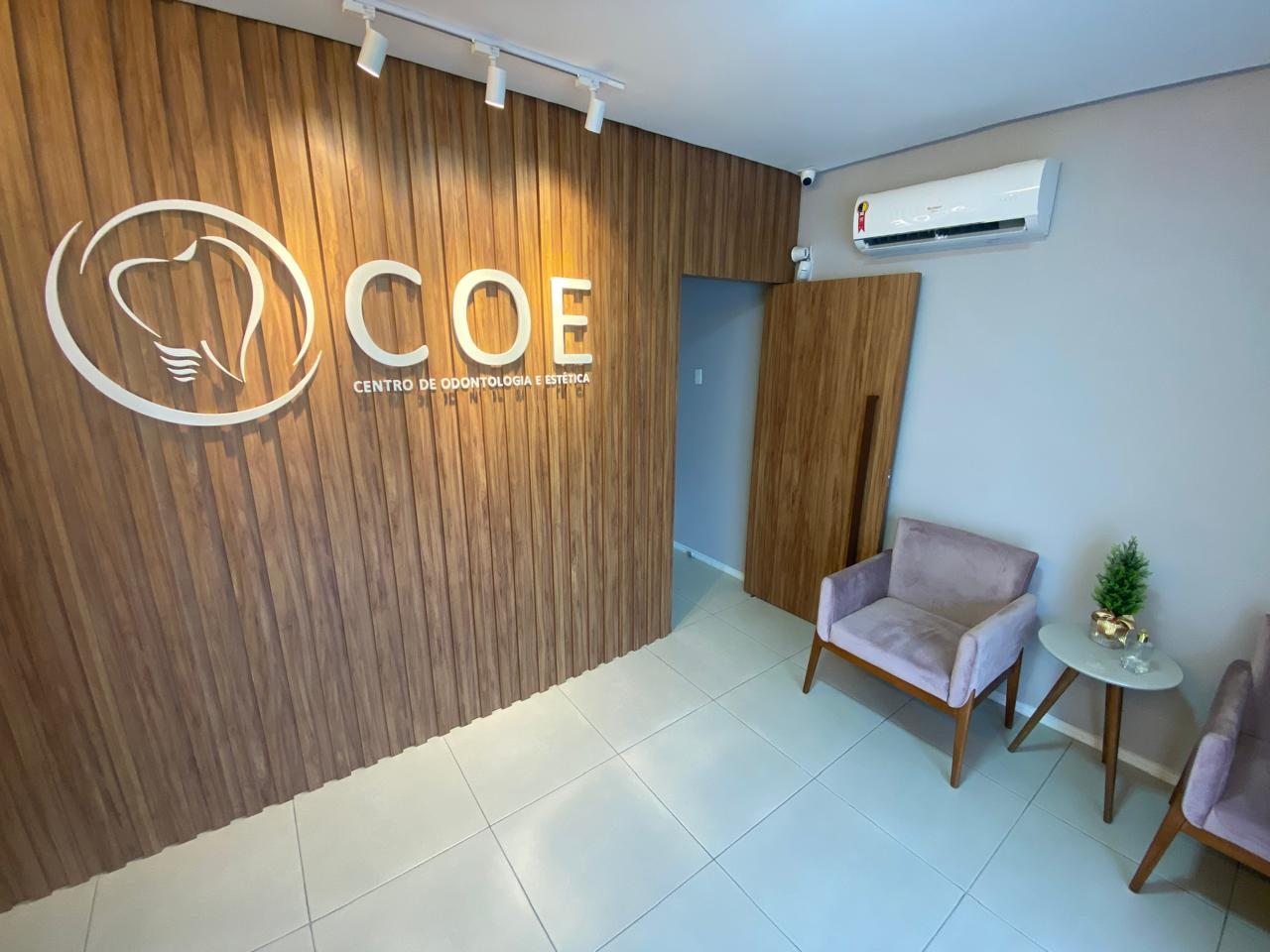 Recepção da COE, com painel de madeira e a logomarca da clínica